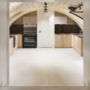 Les meubles sur-mesure, les plans et crédences en quartz et l'électroménager ont pris place. Les tuyauteries d'alimentation existantes, des radiateurs en fonte, les poignées, l'appareillage électrique et les luminaires ont été choisis noirs pour contraster avec les tons chauds de la pierre et des meubles.